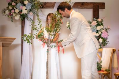 Un couple de mariés ému écoute un joueur de cornemuse, entouré d'invités applaudissant dans une salle lumineuse.