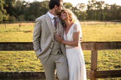 Un couple de mariés ému écoute un joueur de cornemuse, entouré d'invités applaudissant dans une salle lumineuse.