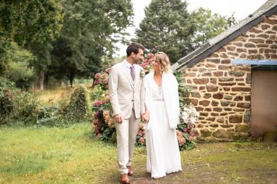 Un couple de mariés ému écoute un joueur de cornemuse, entouré d'invités applaudissant dans une salle lumineuse.
