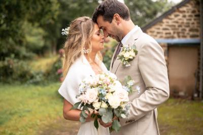 Un couple de mariés ému écoute un joueur de cornemuse, entouré d'invités applaudissant dans une salle lumineuse.