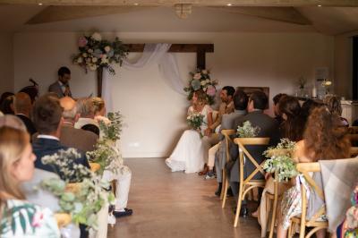 Un couple de mariés ému écoute un joueur de cornemuse, entouré d'invités applaudissant dans une salle lumineuse.