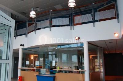 Parking extérieur avec quelques voitures stationnées, entouré de bâtiments modernes et d'arbres alignés.