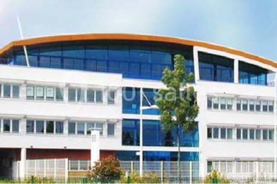 Parking extérieur avec quelques voitures stationnées, entouré de bâtiments modernes et d'arbres alignés.