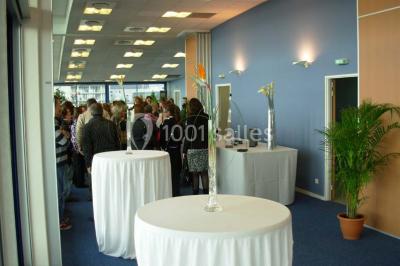 Parking extérieur avec quelques voitures stationnées, entouré de bâtiments modernes et d'arbres alignés.