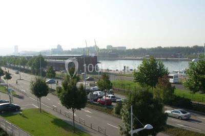 Parking extérieur avec quelques voitures stationnées, entouré de bâtiments modernes et d'arbres alignés.