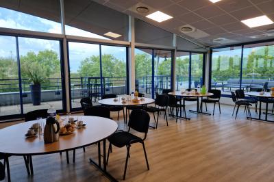 Parking extérieur avec quelques voitures stationnées, entouré de bâtiments modernes et d'arbres alignés.