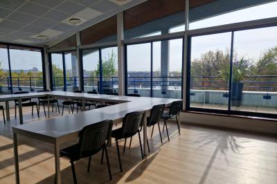 Parking extérieur avec quelques voitures stationnées, entouré de bâtiments modernes et d'arbres alignés.