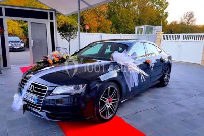 Salle de réception décorée avec des tables rondes, nappes blanches, chaises transparentes et centres de table fleuris.