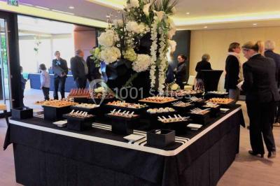 Borne photo interactive sur pied avec écran lumineux, placée à côté d'une mallette noire dans un environnement intérieur.