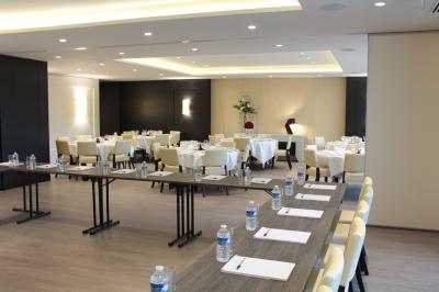 Espace lounge avec canapés blancs, tables basses et vue sur une terrasse arborée avec des tables hautes.