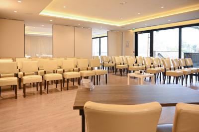 Espace lounge avec canapés blancs, tables basses et vue sur une terrasse arborée avec des tables hautes.