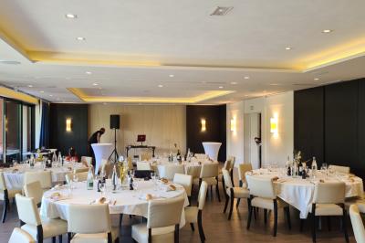 Espace lounge avec canapés blancs, tables basses et vue sur une terrasse arborée avec des tables hautes.