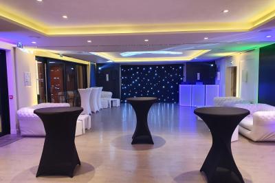 Espace lounge avec canapés blancs, tables basses et vue sur une terrasse arborée avec des tables hautes.