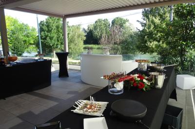 Espace lounge avec canapés blancs, tables basses et vue sur une terrasse arborée avec des tables hautes.