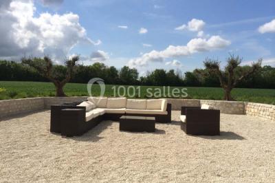 Miniature Location salle Benon (Charente-Maritime) - Abbaye de la Grâce-Dieu #8 Salon lumineux avec murs blancs, plafond voûté, cheminée centrale, meubles anciens et canapés gris.