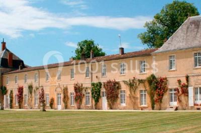 Miniature Location salle Benon (Charente-Maritime) - Abbaye de la Grâce-Dieu #7 Salon lumineux avec murs blancs, plafond voûté, cheminée centrale, meubles anciens et canapés gris.