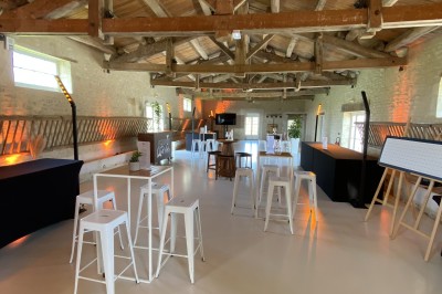 Miniature Location salle Benon (Charente-Maritime) - Abbaye de la Grâce-Dieu #9 Salon lumineux avec murs blancs, plafond voûté, cheminée centrale, meubles anciens et canapés gris.