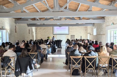 Miniature Location salle Benon (Charente-Maritime) - Abbaye de la Grâce-Dieu #4 Salon lumineux avec murs blancs, plafond voûté, cheminée centrale, meubles anciens et canapés gris.