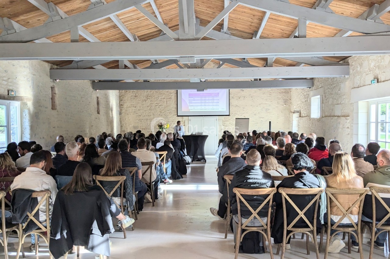 Location salle Benon (Charente-Maritime) - Abbaye de la Grâce-Dieu #4 Salle en pierre avec des poutres apparentes, des personnes assises assistent à une présentation projetée sur un écran.