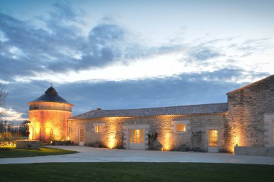 Miniature Location salle Benon (Charente-Maritime) - Abbaye de la Grâce-Dieu #15 Salon lumineux avec murs blancs, plafond voûté, cheminée centrale, meubles anciens et canapés gris.