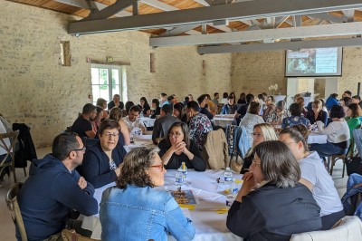 Miniature Location salle Benon (Charente-Maritime) - Abbaye de la Grâce-Dieu #16 Salon lumineux avec murs blancs, plafond voûté, cheminée centrale, meubles anciens et canapés gris.
