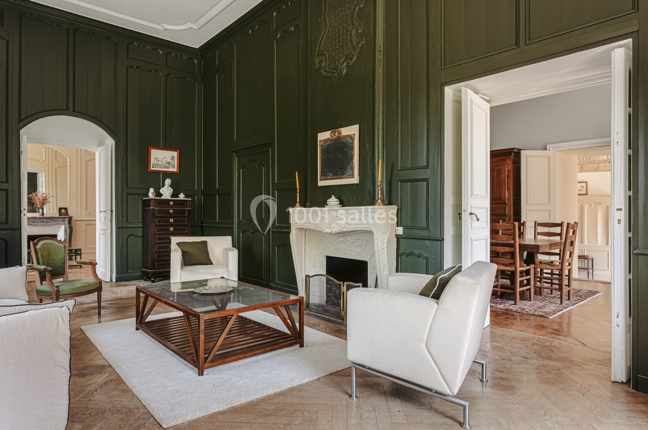 Location salle Benon (Charente-Maritime) - Abbaye de la Grâce-Dieu #17 Salon élégant avec murs vert foncé, cheminée blanche sculptée, mobilier moderne et parquet en bois.