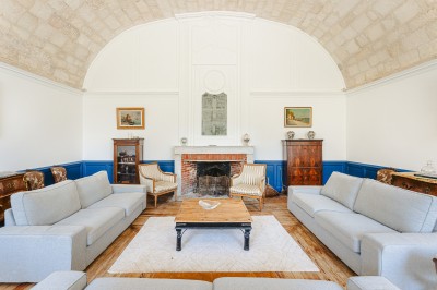 Miniature Location salle Benon (Charente-Maritime) - Abbaye de la Grâce-Dieu #19 Salon lumineux avec murs blancs, plafond voûté, cheminée centrale, meubles anciens et canapés gris.