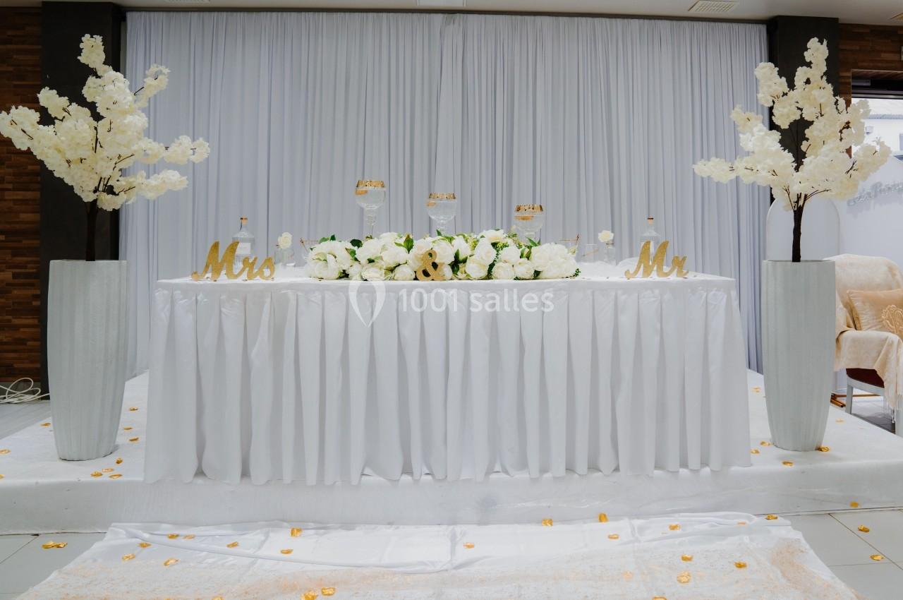 Table décorée pour un mariage avec nappes blanches, fleurs blanches, chandeliers et inscriptions ’Mrs’ et ’Mr’.