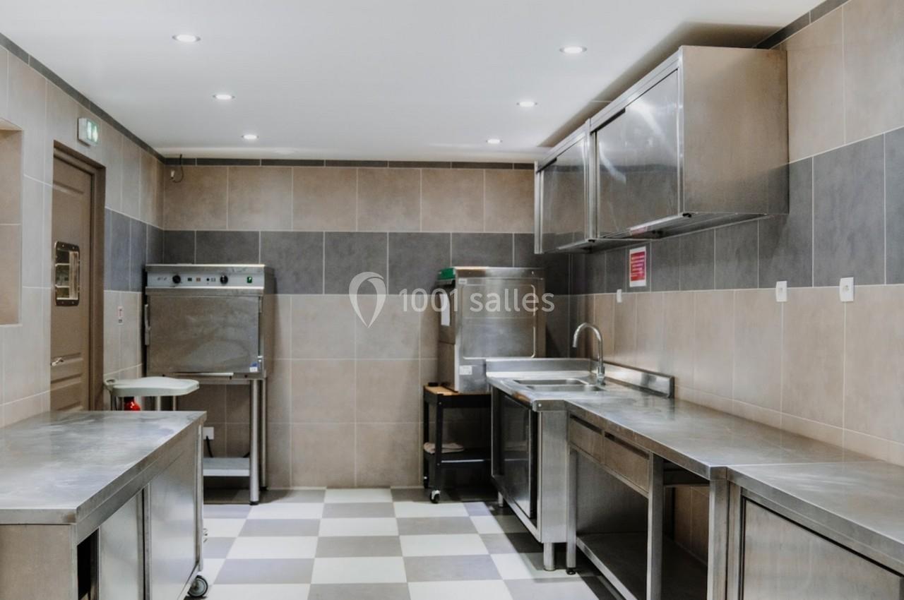 Cuisine professionnelle avec plans de travail en inox, carrelage au sol et équipements de restauration.