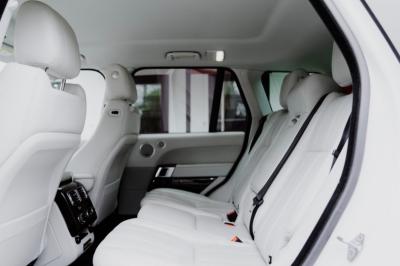 Intérieur d'un véhicule haut de gamme avec volant, tableau de bord et finitions en bois et cuir clair.