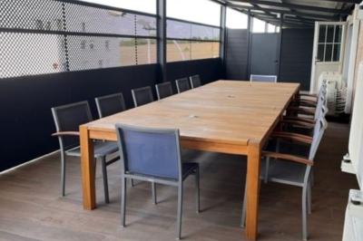 Miniature Location salle Brie-Comte-Robert (Seine-et-Marne) - Event'3 #14 Table en bois rectangulaire entourée de chaises sur une terrasse couverte avec sol en bois et panneaux ajourés.