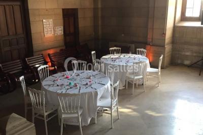 Salle lumineuse avec de grandes fenêtres, tables en bois clair et chaises alignées dans un espace de restauration collectif.