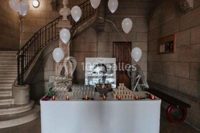 Salle lumineuse avec de grandes fenêtres, tables en bois clair et chaises alignées dans un espace de restauration collectif.