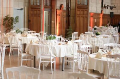 Salle lumineuse avec de grandes fenêtres, tables en bois clair et chaises alignées dans un espace de restauration collectif.