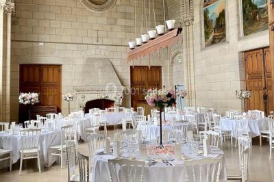 Salle lumineuse avec de grandes fenêtres, tables en bois clair et chaises alignées dans un espace de restauration collectif.