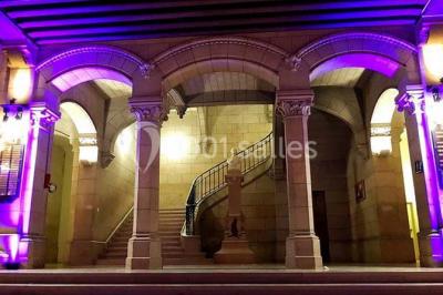 Salle lumineuse avec de grandes fenêtres, tables en bois clair et chaises alignées dans un espace de restauration collectif.