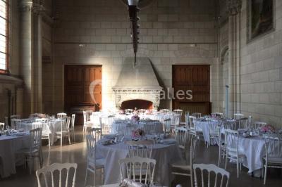 Salle lumineuse avec de grandes fenêtres, tables en bois clair et chaises alignées dans un espace de restauration collectif.