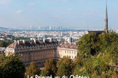 Bâtiment historique avec une chapelle et un terrain de sport au premier plan, sous un ciel partiellement nuageux.