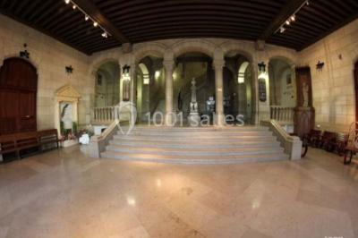 Bâtiment historique avec une chapelle et un terrain de sport au premier plan, sous un ciel partiellement nuageux.