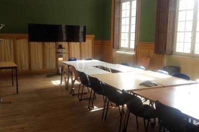 Bâtiment historique avec une chapelle et un terrain de sport au premier plan, sous un ciel partiellement nuageux.