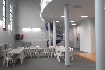 Bâtiment historique avec une chapelle et un terrain de sport au premier plan, sous un ciel partiellement nuageux.