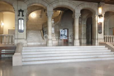 Bâtiment historique avec une chapelle et un terrain de sport au premier plan, sous un ciel partiellement nuageux.