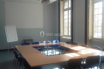 Bâtiment historique avec une chapelle et un terrain de sport au premier plan, sous un ciel partiellement nuageux.