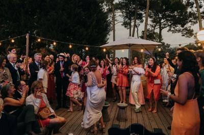 Bar animé avec des lumières colorées, des clients discutant et des paniers suspendus en décoration.