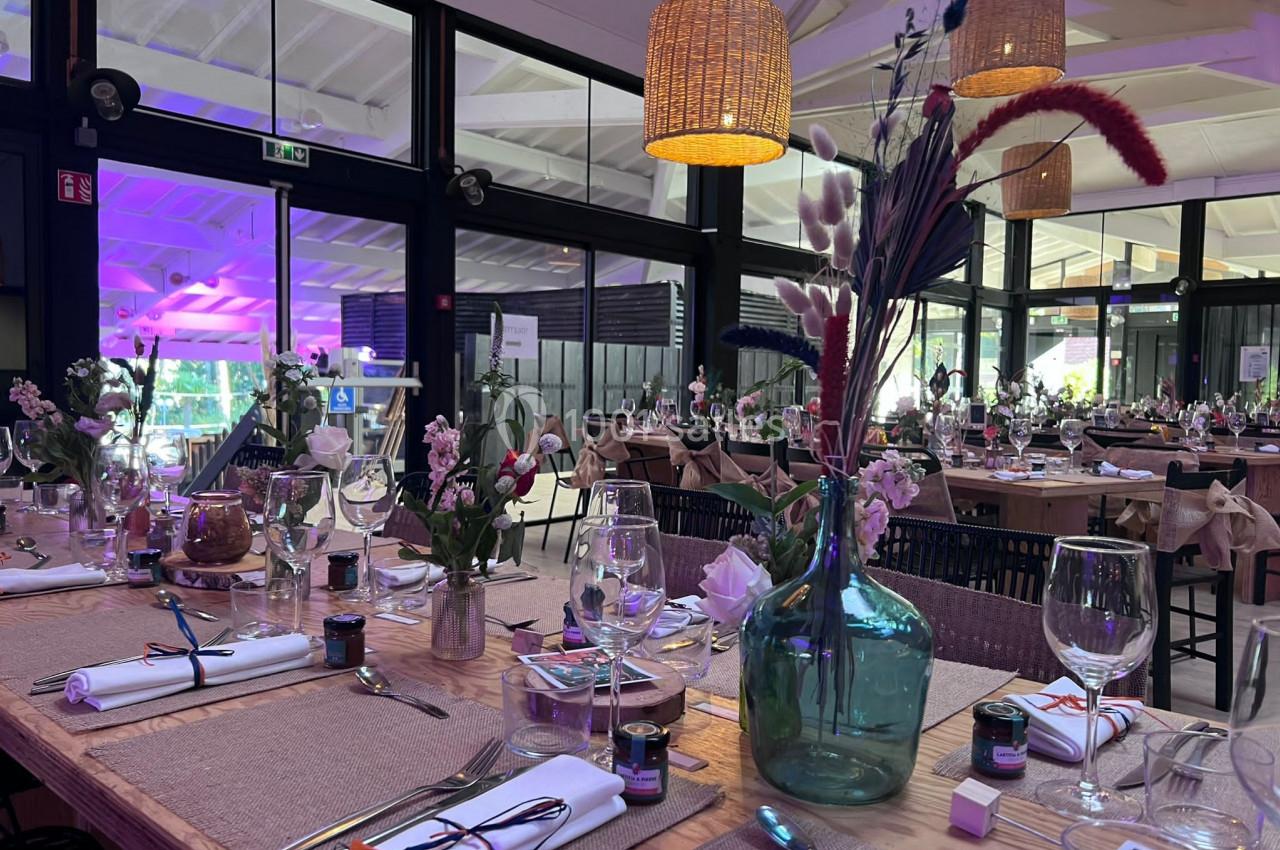 Salle de réception décorée avec des tables dressées, ornées de fleurs et de détails champêtres.