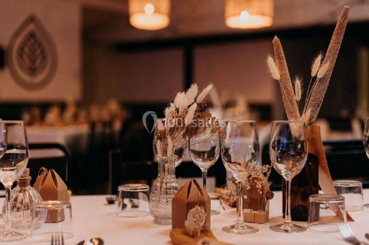 Table dressée avec élégance, décorée de fleurs séchées, verres à pied et petits objets en bois dans une ambiance chaleureuse.