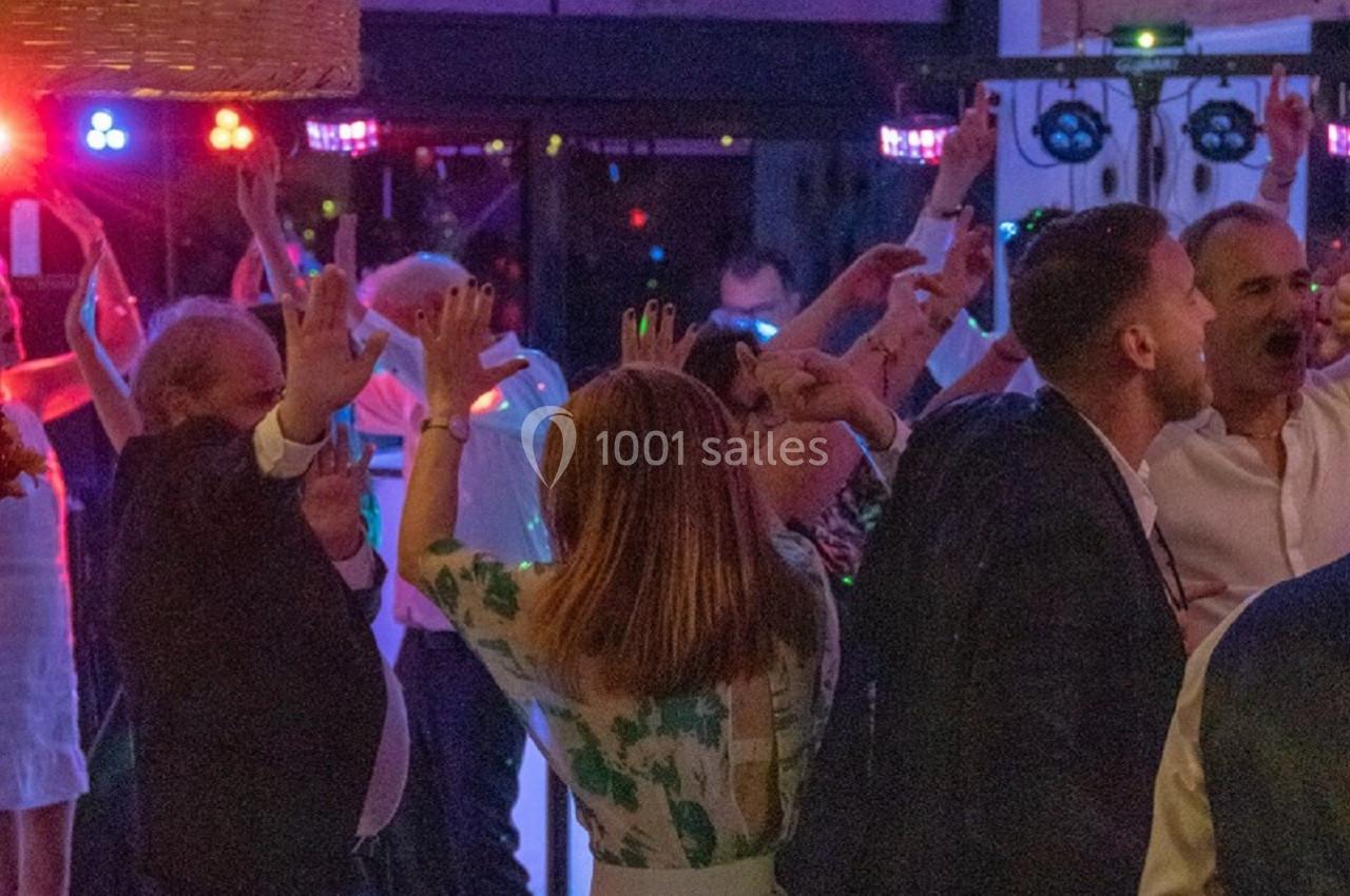 Des personnes dansent et s'amusent sous des lumières colorées dans une salle décorée avec des lampes suspendues.