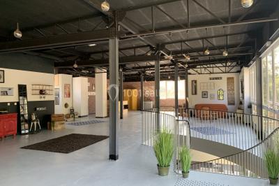 Salle de réception décorée avec des tables rondes, nappes blanches, serviettes orange et chaises blanches.