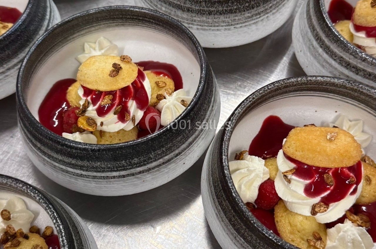 Desserts individuels dans des bols en céramique, composés de crème, coulis rouge, biscuits et éclats croustillants.
