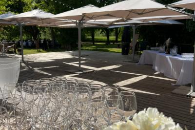Salle de réception décorée avec des tables rondes, nappes blanches, serviettes orange et chaises blanches.
